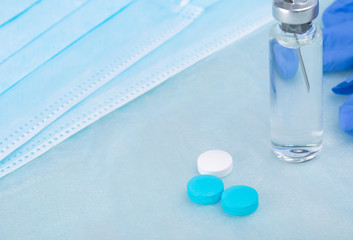 against the background of medical masks and sterile tissue, a drug in an ampoule and pills to increase immunity