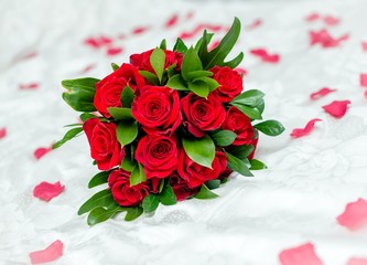 The bride's bouquet of red roses lies on a white cloth