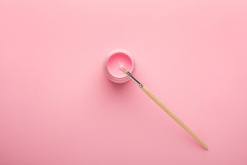 Pink acrylic paint with a brush on pink background, simple pastel composition