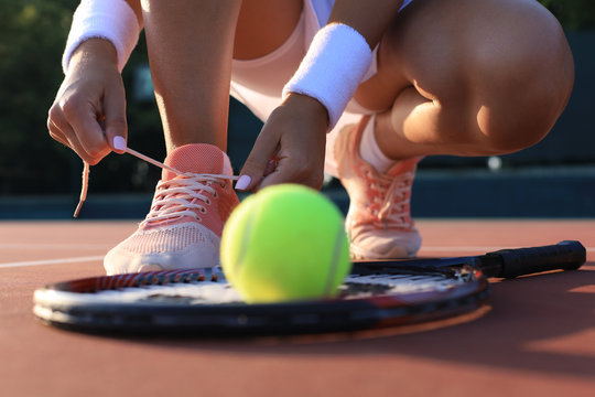 Sports woman getting ready for playing tennis tying shoelaces on outdoor.