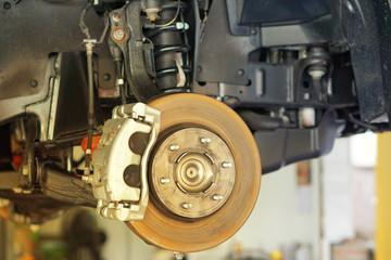 car brake part at garage,car brake disc without wheels.Disk brake and car disk brake system service concept - Car disk brake pad replacement service by hand of mechanic man in car garage.Close up.