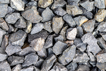 Top view on several grey pebbles lying on the ground at the riverside of a lake 