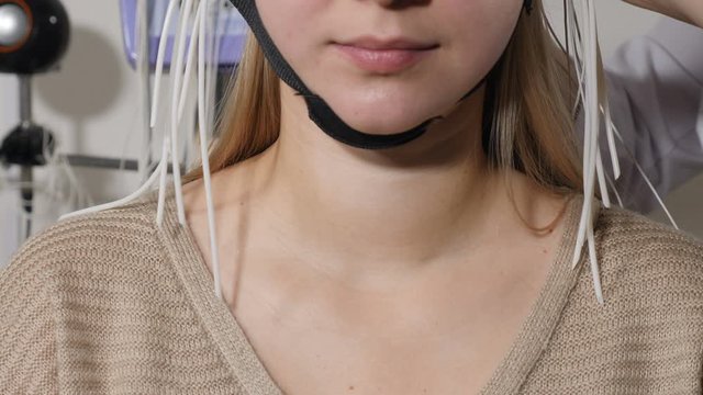 Electroencephalographic examination in clinic. Equipment for receiving brain EEG human. Female patient wired to EEG machine or electroencephalograph which produces graphical record of brain electrical