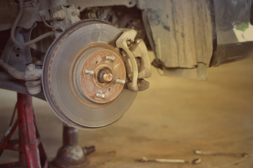 car brake part at garage,car brake disc without wheels.Disk brake and car disk brake system service concept - Car disk brake pad replacement service by hand of mechanic man in car garage.Close up.