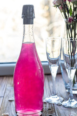 Sparkling brilliant raspberry drink. Champagne in two glasses stands on a wooden table with ice....