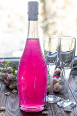 Sparkling brilliant raspberry drink. Champagne in two glasses stands on a wooden table with ice. For flowers and a garland.