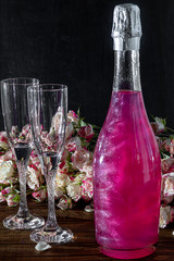 Sparkling brilliant raspberry drink. Champagne in two glasses stands on a wooden table with ice....