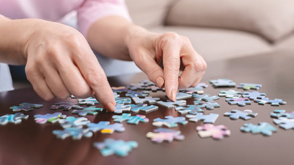 Senior woman playing jigsaw puzzle at home, empty space