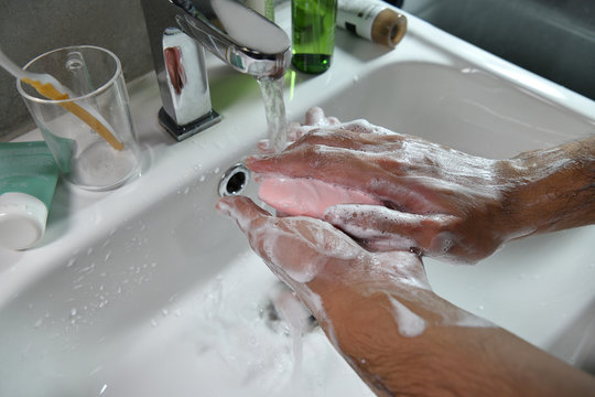 Hands being washed scrubbed and rinsed using disinfectant soap for hygiene and protection against COVID-19 and other dieseases