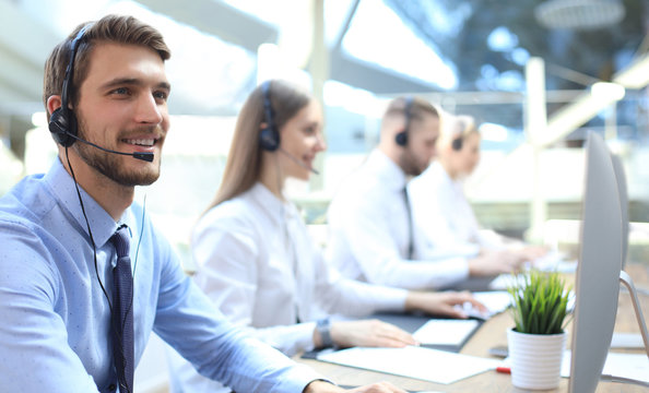Portrait of call center worker accompanied by his team. Smiling customer support operator at work.