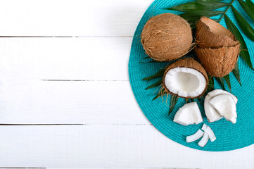 Fototapeta na wymiar Coconut. Whole coconut, shell and green leaves on a white wooden background. Big nut. Tropical fruit coconut in the shell. SPA. Food photo. Photo background. Texture tropical fruit. Copy spase.