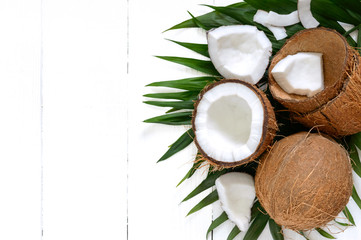 Obraz na płótnie Canvas Coconut. Whole coconut, shell and green leaves on a white wooden background. Big nut. Tropical fruit coconut in the shell. SPA. Food photo. Photo background. Texture tropical fruit. Copy spase.