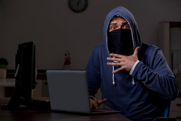 Male hacker hacking security firewall late in office