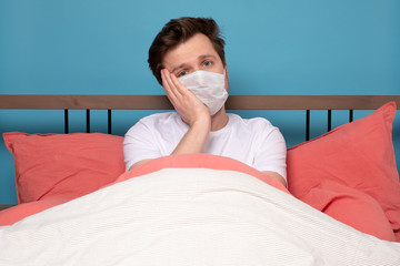Sick mature caucasian man lying down in bed wearing mask protection mask