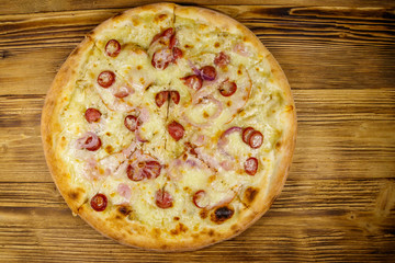 Delicious fresh pizza with sausage, red onion and cheese on a wooden table. Top view