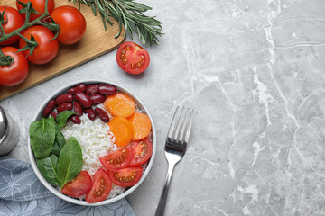 Tasty rice with beans served on light grey marble table, flat lay. Space for text