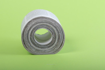 toilet paper made out of newspapers, alternative toilet paper, isolated on green, newspaper roll