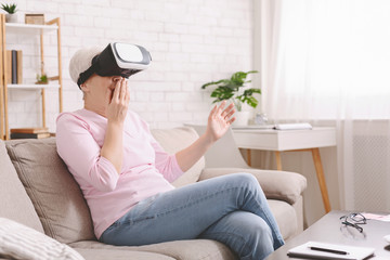 Amazed senior woman enjoying realism of VR at home