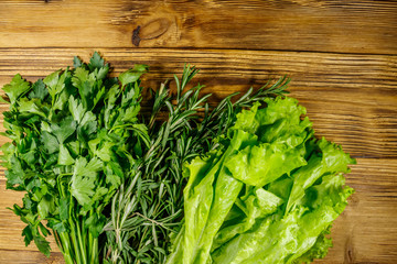 Fresh green parsley, lettuce leaves and rosemary herbs on wooden table. Top view