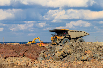 Huge yellow mining dump truck working in iron ore quarry. Mining industry © olyasolod