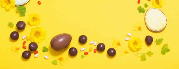 Easter yellow background with chocolatte eggs,    candy and spri
