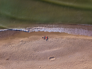Drone photo. The couple lies on the beach. Top view