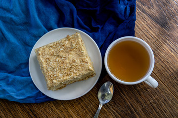 Cup of tea with cake on brown table background