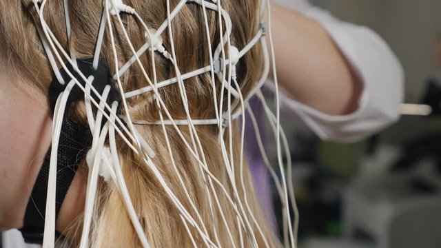 Electroencephalographic examination in clinic. Equipment for receiving brain EEG human. Female patient wired to EEG machine or electroencephalograph which produces graphical record of brain electrical
