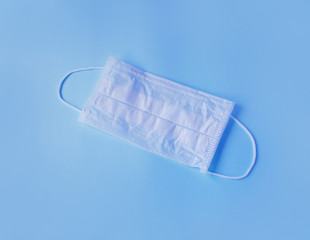 protective white medical mask on a blue background, a means of protection against the virus