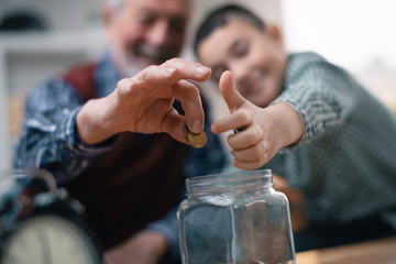 Grandpa and grandson saving money. Grandfather teaching grandchild how to save money.