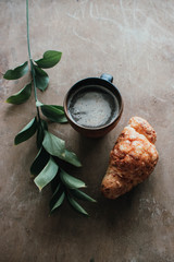 Cappuccino coffee and croissant on wooden background on the table. Perfect breakfast in the morning. Rustic candid style.