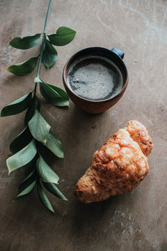 Cappuccino coffee and croissant on wooden background on the table. Perfect breakfast in the morning. Rustic candid style.