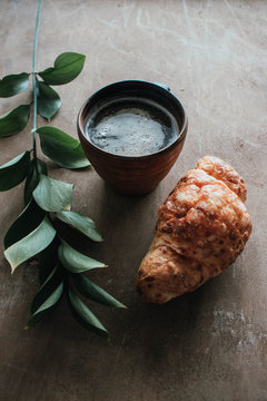 Cappuccino coffee and croissant on wooden background on the table. Perfect breakfast in the morning. Rustic candid style.