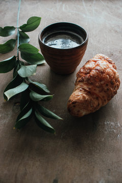Cappuccino coffee and croissant on wooden background on the table. Perfect breakfast in the morning. Rustic candid style.