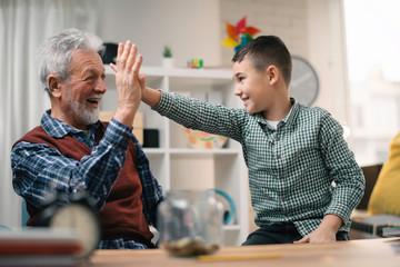 Grandpa and grandson saving money. Grandfather teaching grandchild how to save money.