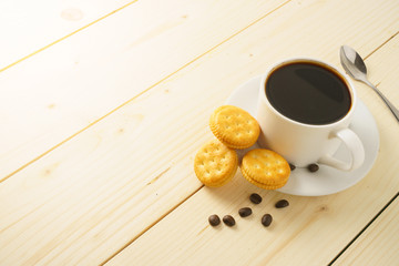 coffee cup with beans and biscuits on wooden desk. copy space for your text