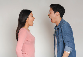 Asian man and woman shouting over grey background