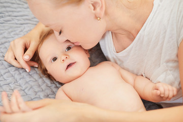 Mother hugging her baby lying on a bed