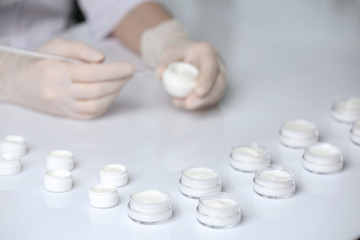 Fototapeta na wymiar Scientist working in laboratory, focus on jars with different cosmetic products