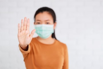 Asian woman wear a mask to prevent germs and standing and raising hand to show the symbol of wrong...