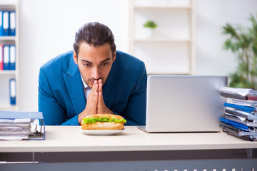 Fototapeta na wymiar Young male employee having breakfast at workplace
