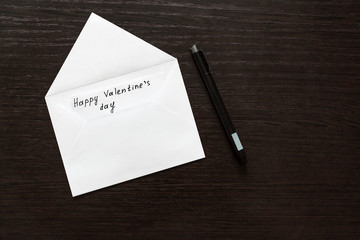 An empty white envelope and a sheet of paper with a pen on the background of a wooden table