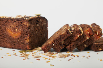 fresh bread with various seeds (pumpkin, dried apricots, flax, sunflower, sesame, prunes) is decorated with wheat ears isolated on a white background.