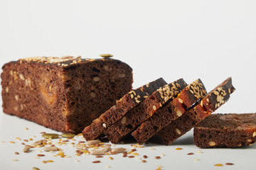 fresh bread with various seeds (pumpkin, dried apricots, flax, sunflower, sesame, prunes) is decorated with wheat ears isolated on a white background.