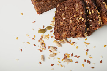 fresh bread with various seeds (pumpkin, dried apricots, flax, sunflower, sesame, prunes) is decorated with wheat ears isolated on a white background.