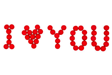Fototapeta premium Letters and a heart made of red candies on a white background are laid out
