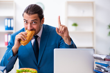 Young male employee having breakfast at workplace
