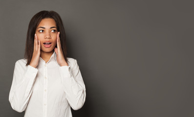 Black woman surprised on gray background with copy space