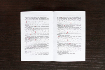 Fototapeta premium Open book on the background of a wooden table. The book highlights the letters from the inscription-I love you.