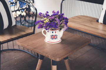 Purple flowers are in a pot with an English flag on a wooden desk.